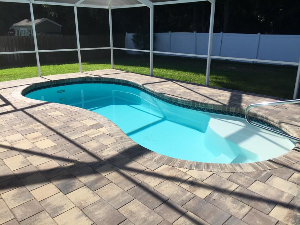 На фото: спортивный бассейн среднего размера, в форме фасоли на заднем дворе в классическом стиле с домиком у бассейна и покрытием из плитки
