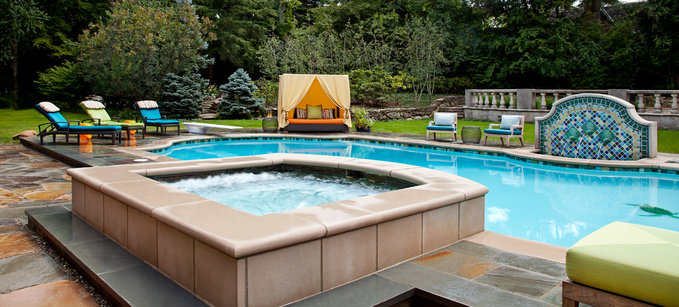 Foto de piscinas y jacuzzis alargados tradicionales grandes a medida en patio trasero con adoquines de piedra natural