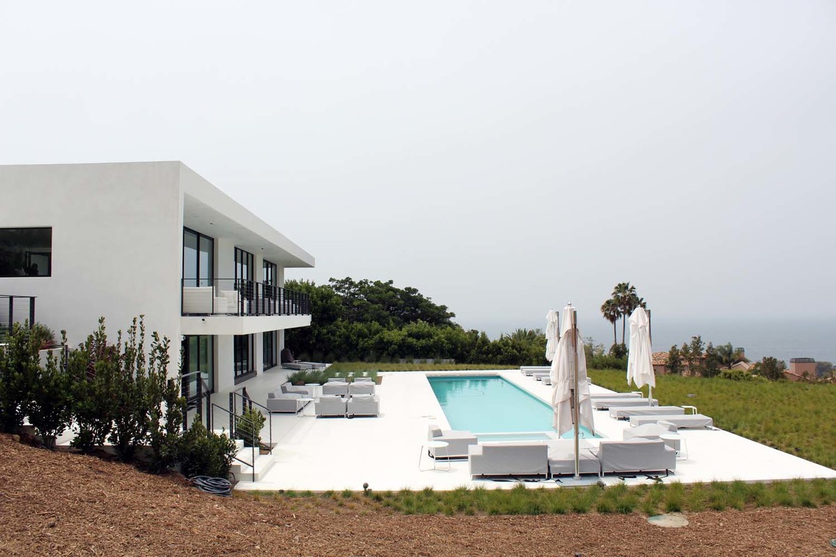 Imagen de piscina alargada minimalista grande rectangular en patio trasero con losas de hormigón
