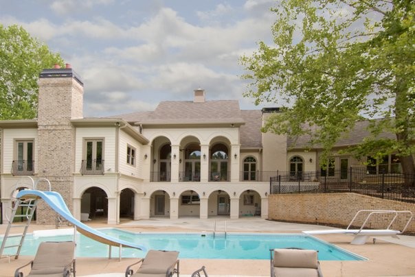 Inspiration för en mycket stor medelhavsstil anpassad pool på baksidan av huset, med vattenrutschkana och betongplatta