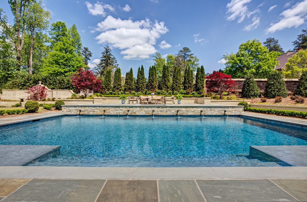 Foto på en medelhavsstil pool på baksidan av huset, med en fontän och naturstensplattor