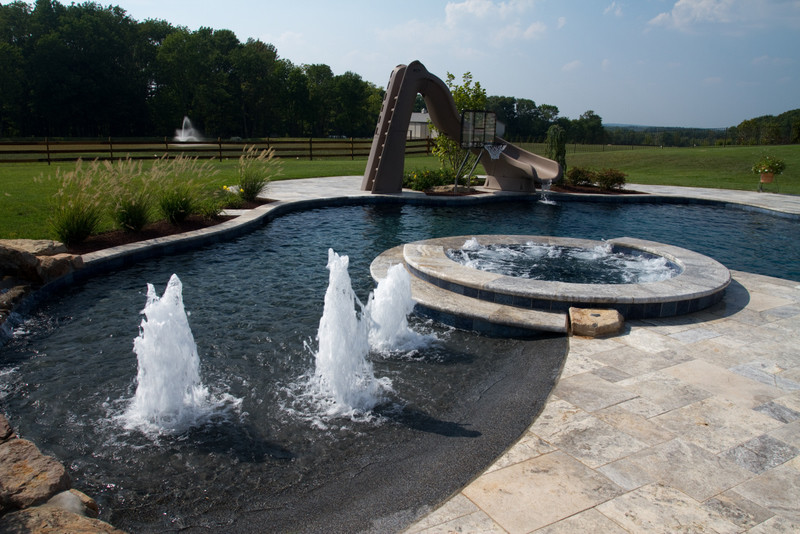 Diseño de piscina con fuente moderna extra grande a medida en patio trasero con granito descompuesto