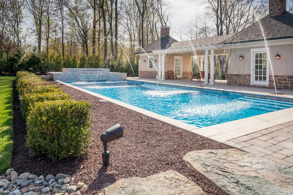 Photo of a medium sized classic back rectangular swimming pool in Newark with a water feature and concrete paving.