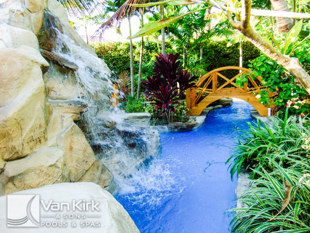 Cette photo montre une très grande piscine naturelle et arrière exotique sur mesure avec un point d'eau et des pavés en pierre naturelle.