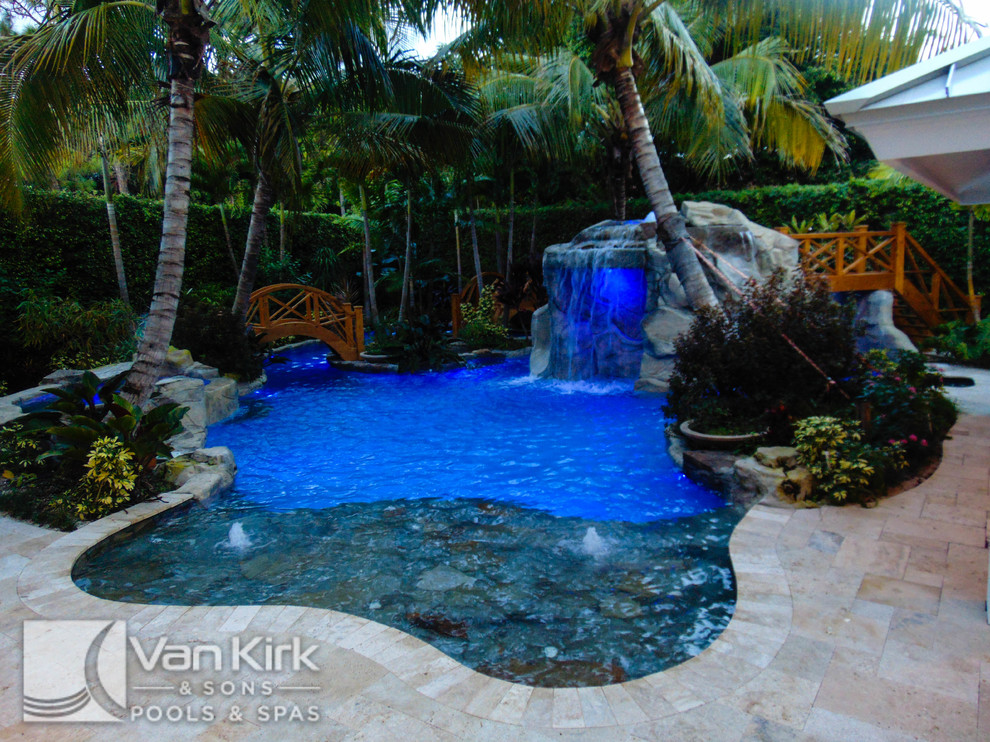 На фото: огромный естественный бассейн произвольной формы на заднем дворе в морском стиле с фонтаном и покрытием из каменной брусчатки с