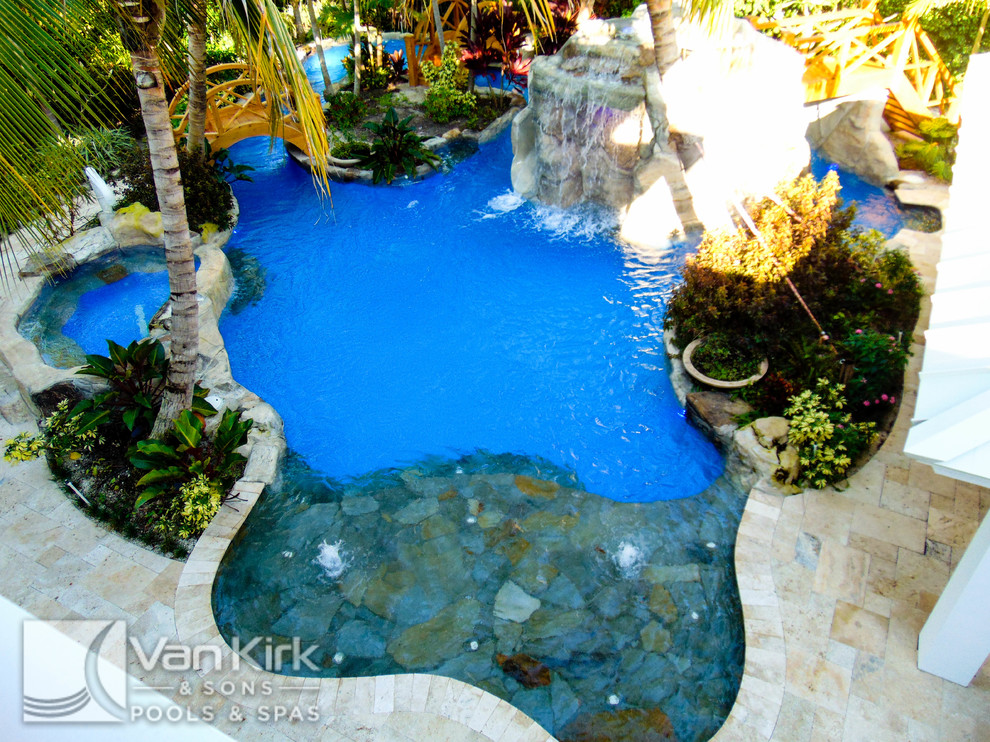 Esempio di un'ampia piscina naturale tropicale personalizzata dietro casa con fontane e pavimentazioni in pietra naturale