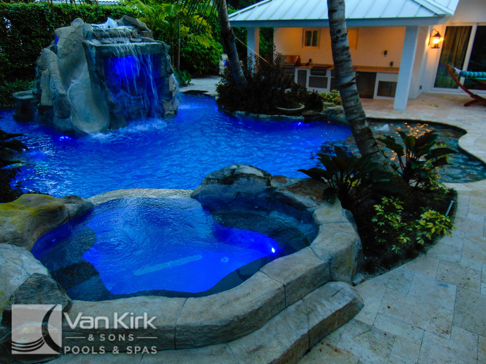 Idéer för att renovera en mycket stor tropisk anpassad baddamm på baksidan av huset, med en fontän och naturstensplattor