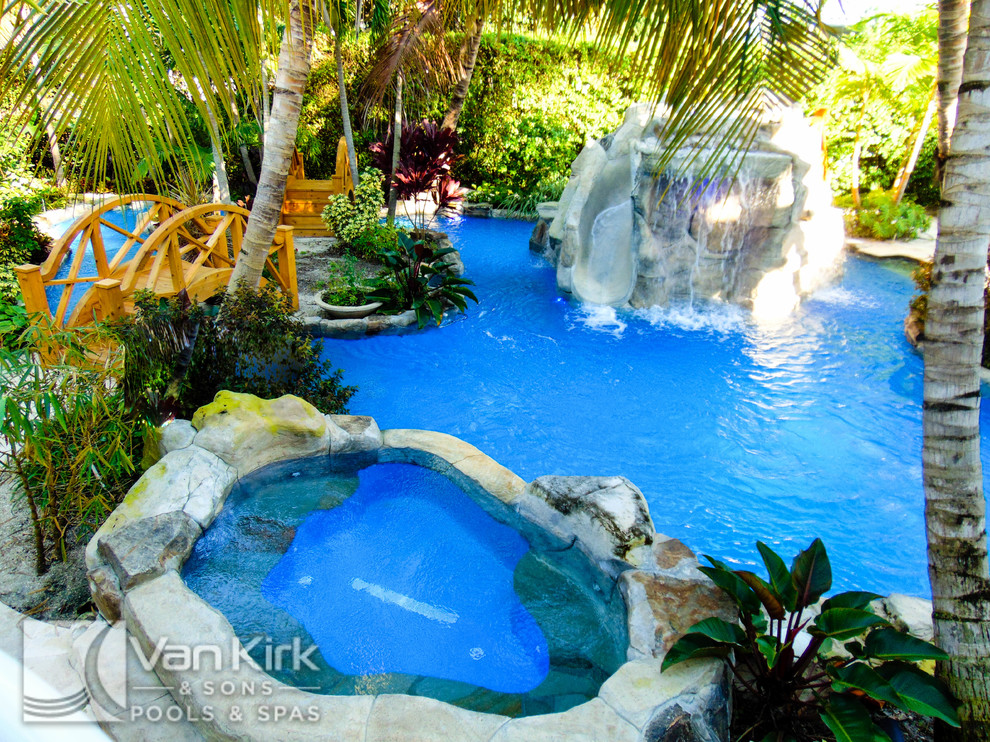 Esempio di un'ampia piscina naturale tropicale personalizzata dietro casa con fontane e pavimentazioni in pietra naturale