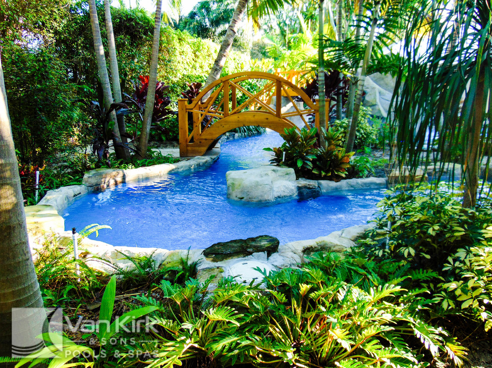 Cette image montre une très grande piscine naturelle et arrière ethnique sur mesure avec un point d'eau et des pavés en pierre naturelle.