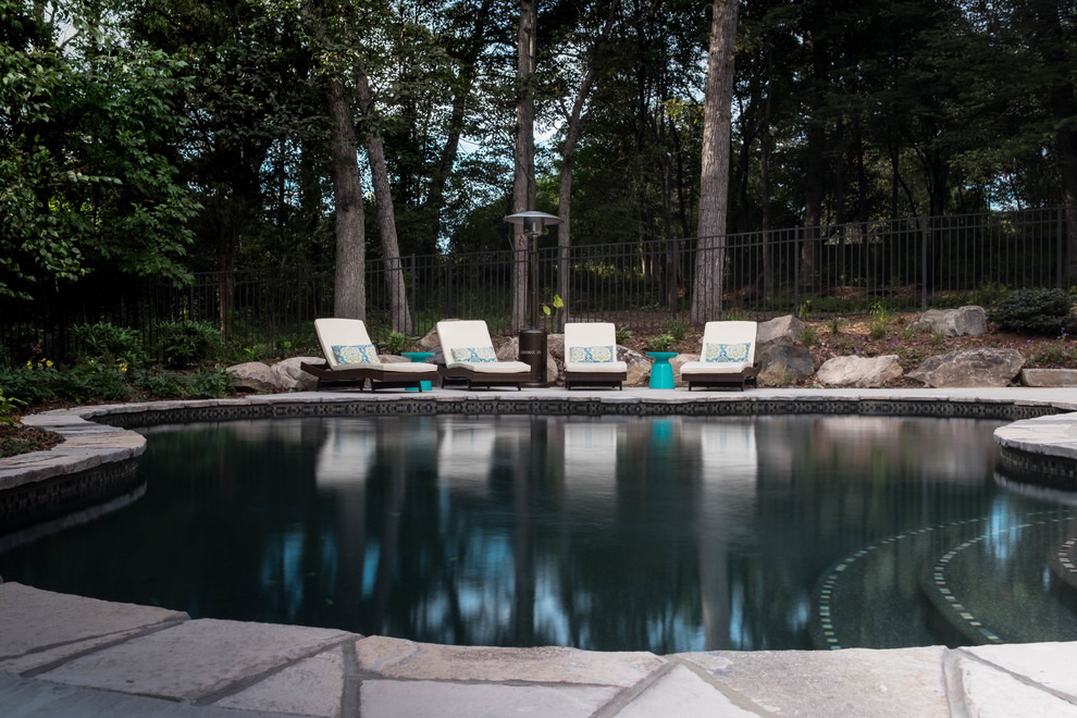 Photo of a medium sized traditional back custom shaped natural swimming pool in Grand Rapids with a water feature and natural stone paving.