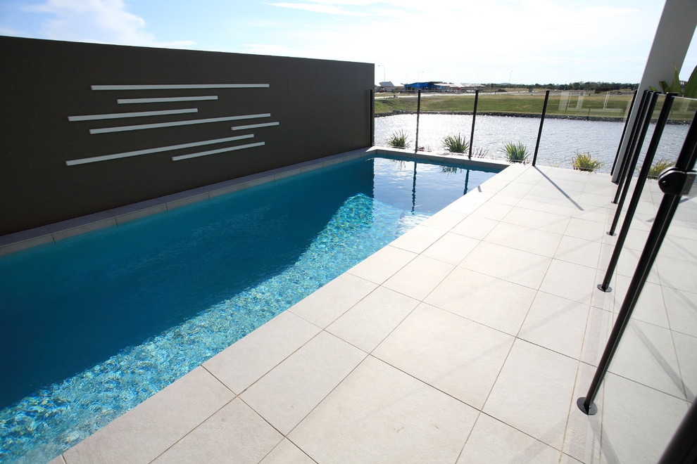 Пример оригинального дизайна: спортивный, прямоугольный бассейн среднего размера на заднем дворе в стиле модернизм с покрытием из плитки