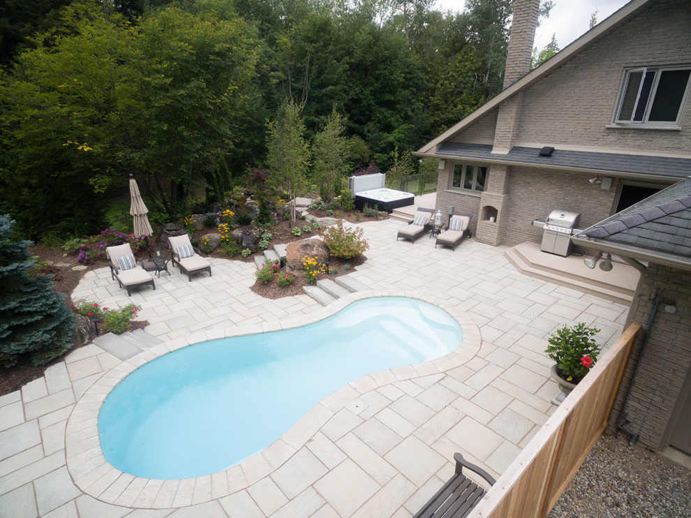 Diseño de piscina rural de tamaño medio en patio trasero con adoquines de hormigón