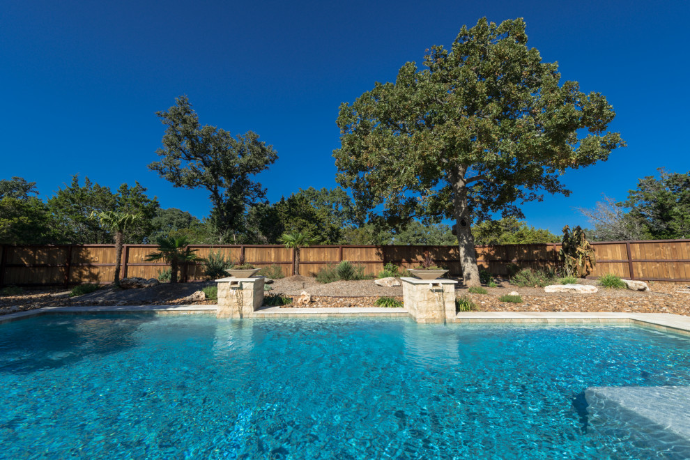 Immagine di una grande piscina design rettangolare dietro casa con fontane e pedane