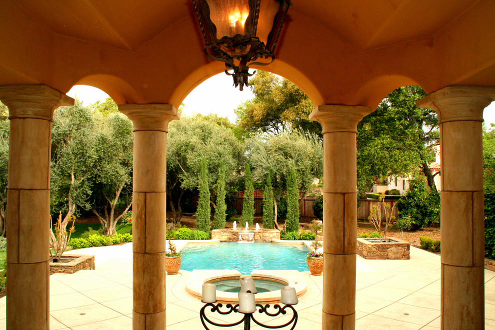 Ispirazione per una piscina monocorsia stile americano rettangolare di medie dimensioni e dietro casa con fontane e lastre di cemento