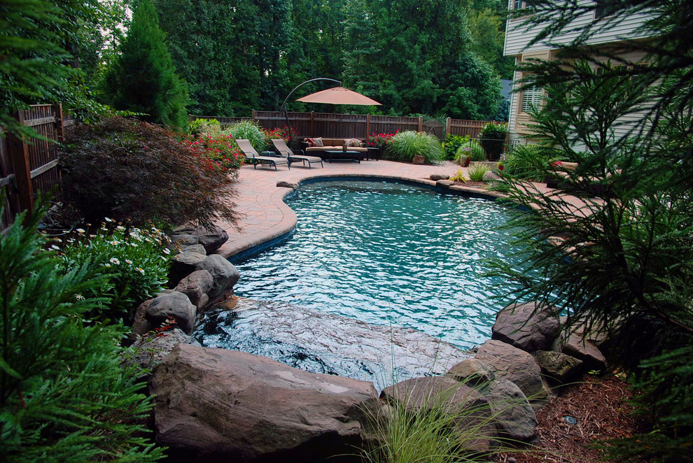 На фото: естественный бассейн среднего размера, произвольной формы на заднем дворе в стиле фьюжн с фонтаном и мощением тротуарной плиткой