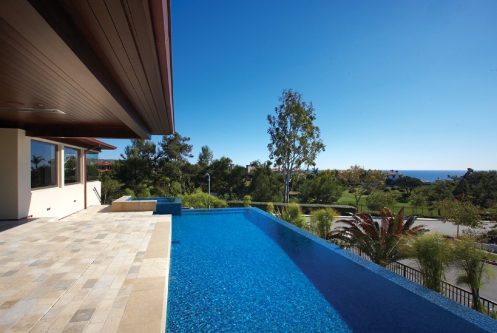 Example of a trendy backyard tile and rectangular infinity hot tub design in Orange County