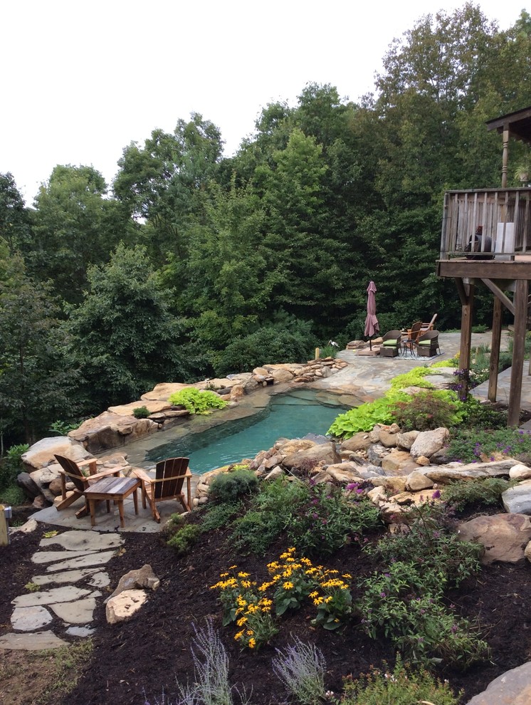 Cette photo montre une piscine naturelle et arrière exotique de taille moyenne et sur mesure avec un point d'eau et des pavés en pierre naturelle.
