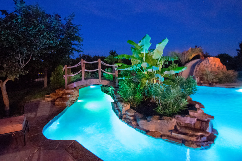 Foto på en mycket stor rustik pool på baksidan av huset, med vattenrutschkana och naturstensplattor