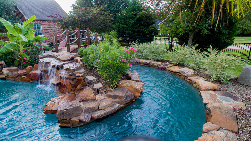 Ejemplo de piscina con tobogán rural extra grande a medida en patio trasero con adoquines de piedra natural