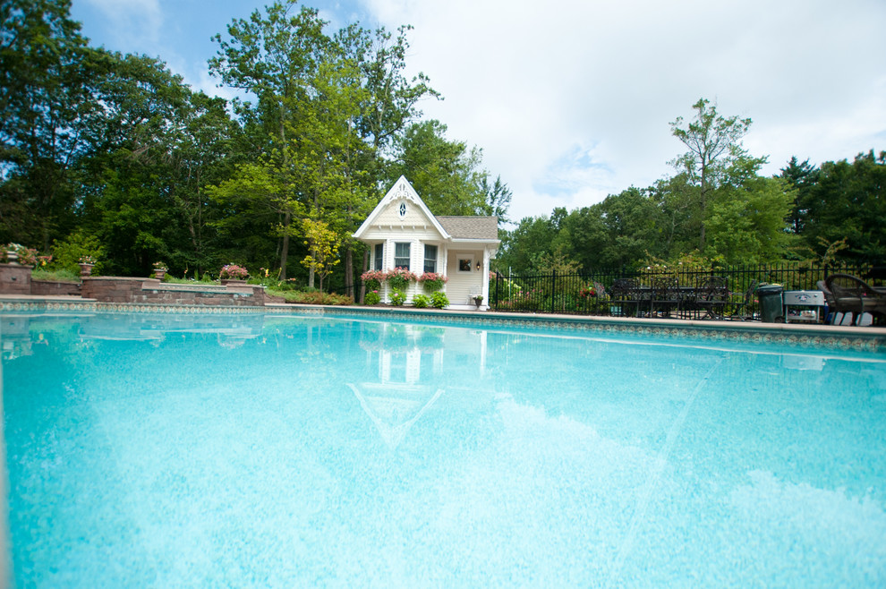 Foto de casa de la piscina y piscina alargada clásica de tamaño medio rectangular en patio trasero con adoquines de piedra natural