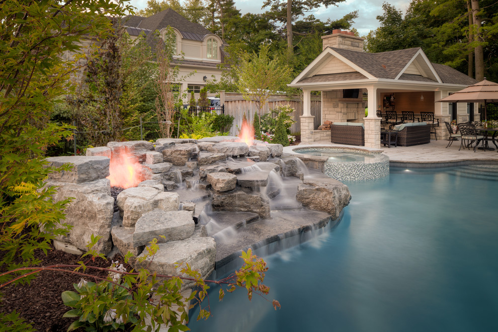 На фото: большой естественный бассейн произвольной формы на заднем дворе в классическом стиле с джакузи с