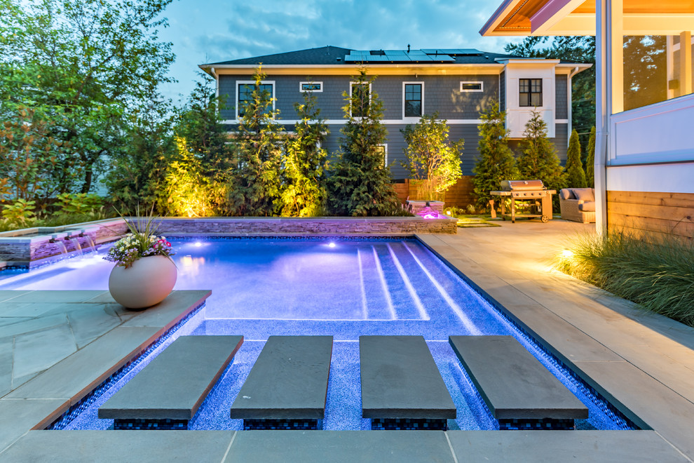 Imagen de piscina con fuente minimalista pequeña rectangular en patio trasero con adoquines de piedra natural