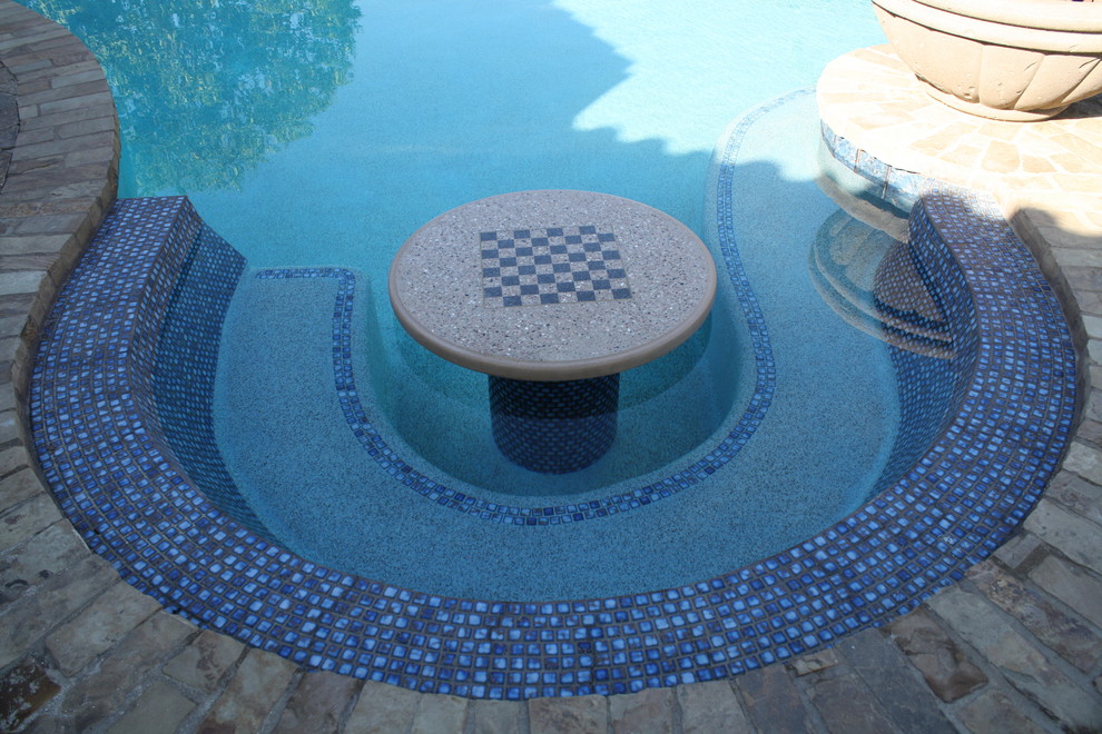 Design ideas for a medium sized traditional back custom shaped natural swimming pool in Los Angeles with brick paving.