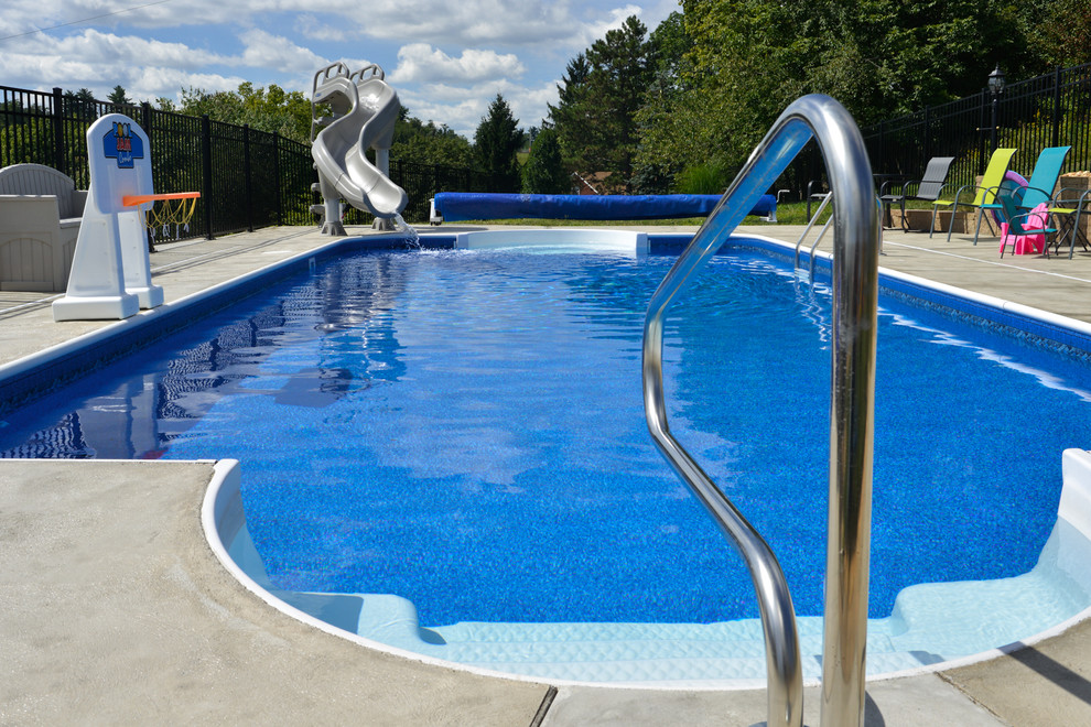 На фото: прямоугольный бассейн среднего размера на заднем дворе в стиле модернизм с водной горкой и покрытием из бетонных плит