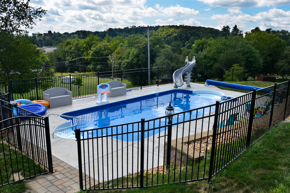 Ispirazione per una piscina minimalista rettangolare di medie dimensioni e dietro casa con un acquascivolo e lastre di cemento