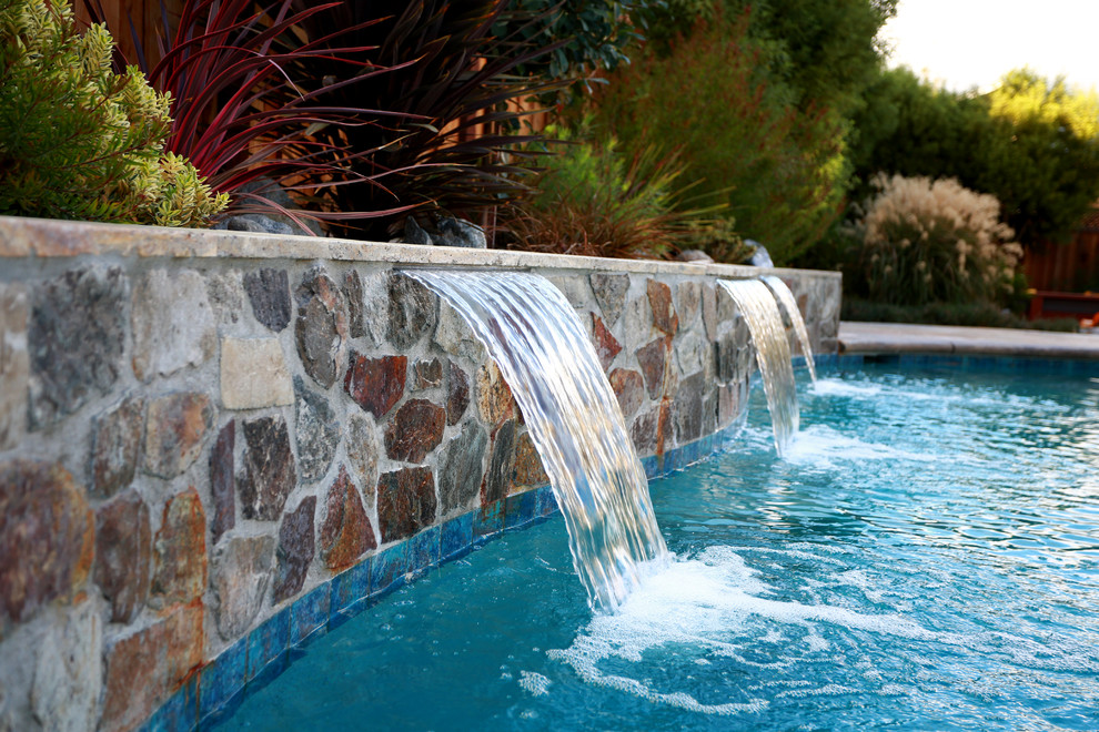 На фото: наземный бассейн среднего размера, произвольной формы на заднем дворе в современном стиле с фонтаном и покрытием из каменной брусчатки с