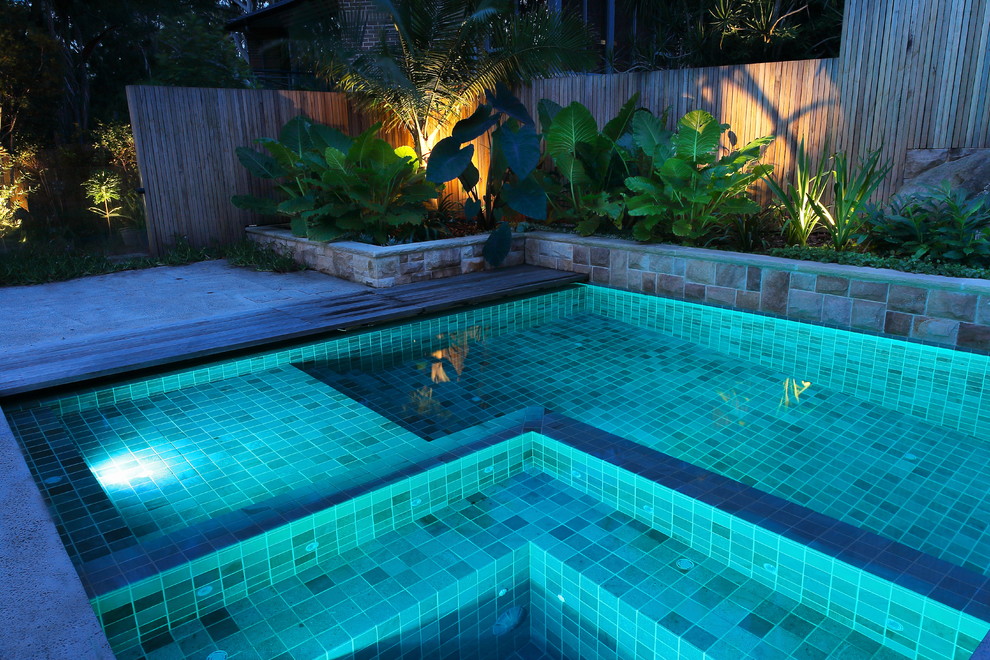 Ejemplo de piscina con tobogán alargada actual de tamaño medio rectangular en patio lateral con losas de hormigón