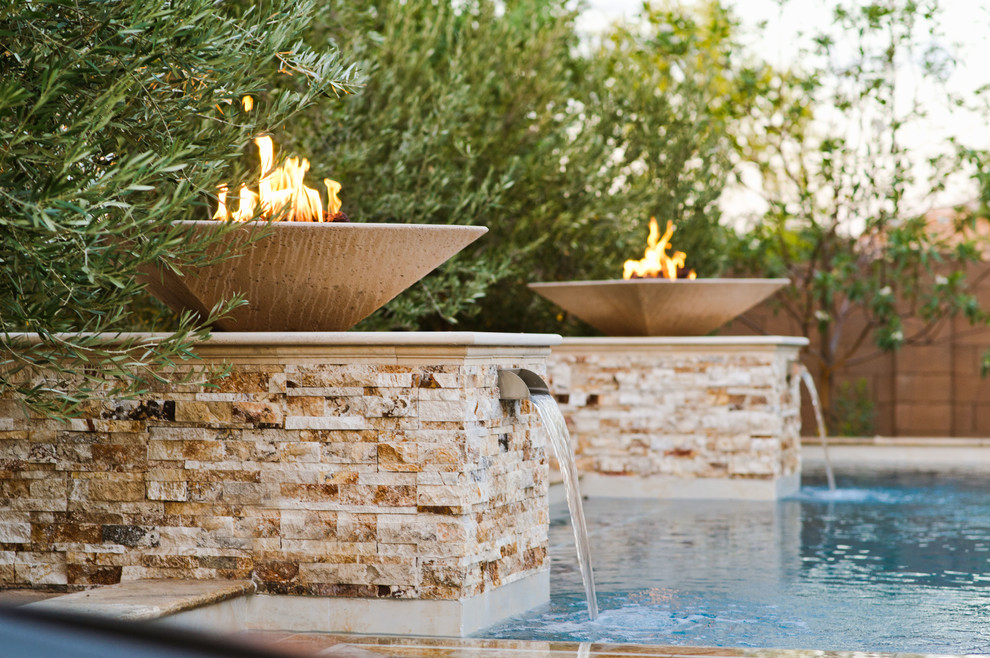 Diseño de piscina con fuente infinita actual grande a medida en patio trasero con adoquines de piedra natural