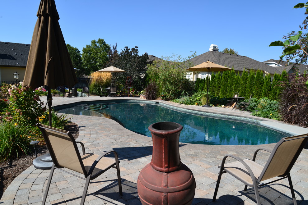 Modelo de piscina minimalista grande a medida en patio trasero con adoquines de piedra natural