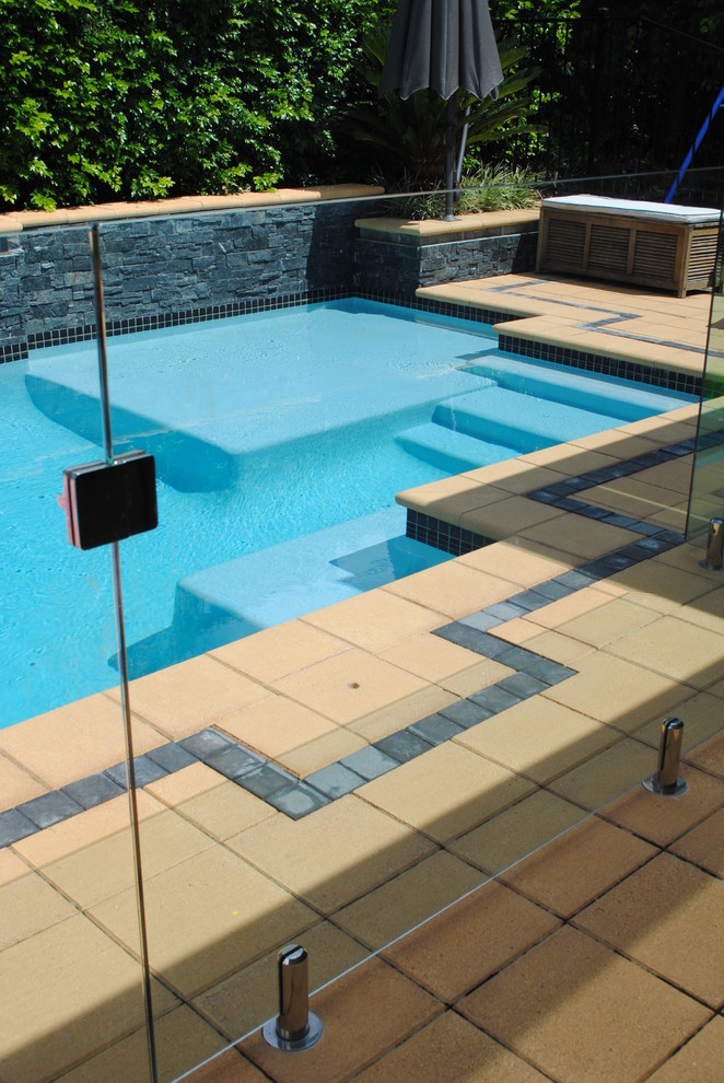 This is an example of a small contemporary back rectangular lengths swimming pool in Sydney with a water feature and tiled flooring.