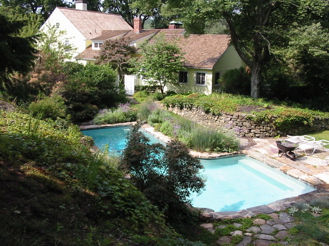 Bild på en mellanstor lantlig anpassad baddamm på baksidan av huset, med marksten i betong