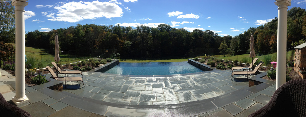 Example of a mid-sized trendy backyard stone and rectangular infinity pool design in New York
