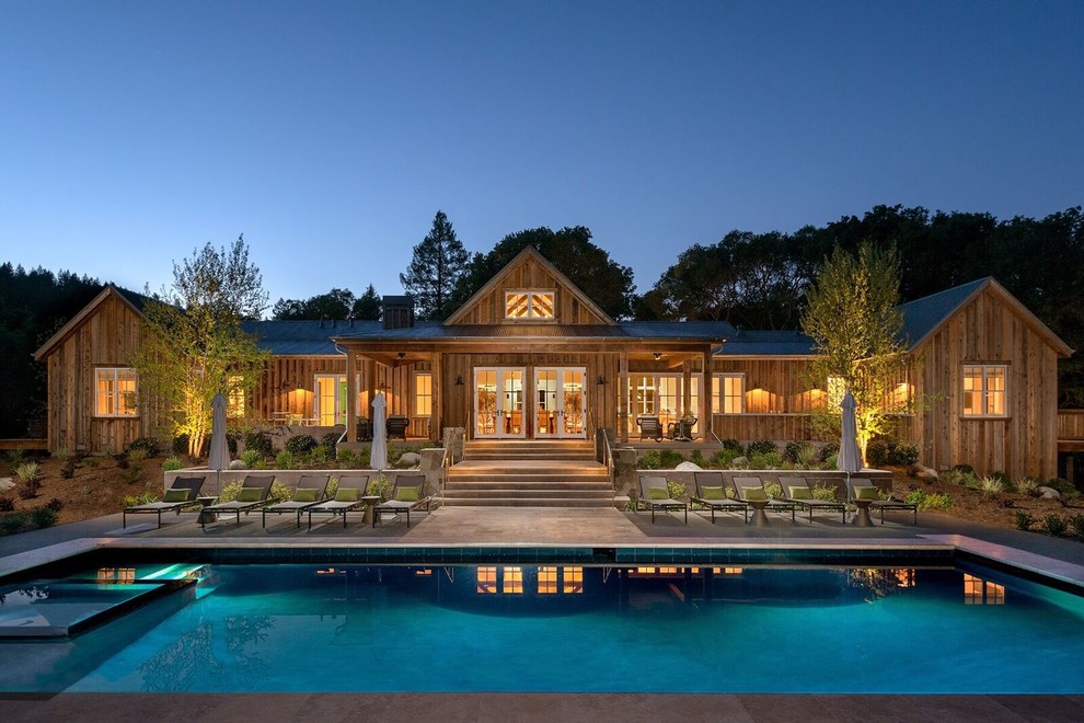 Imagen de piscinas y jacuzzis alargados de estilo de casa de campo grandes rectangulares en patio trasero con losas de hormigón