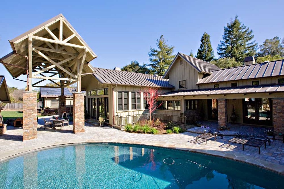 Immagine di un'ampia piscina classica personalizzata dietro casa con pavimentazioni in pietra naturale