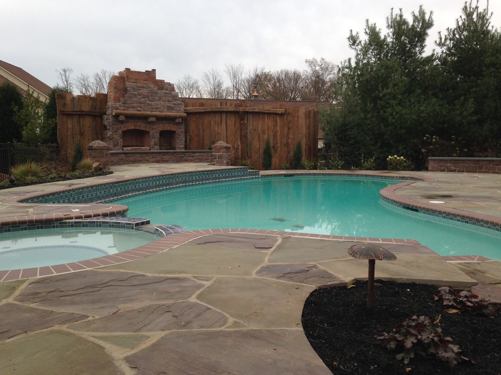 Photo of a large country back kidney-shaped swimming pool in Philadelphia with natural stone paving.