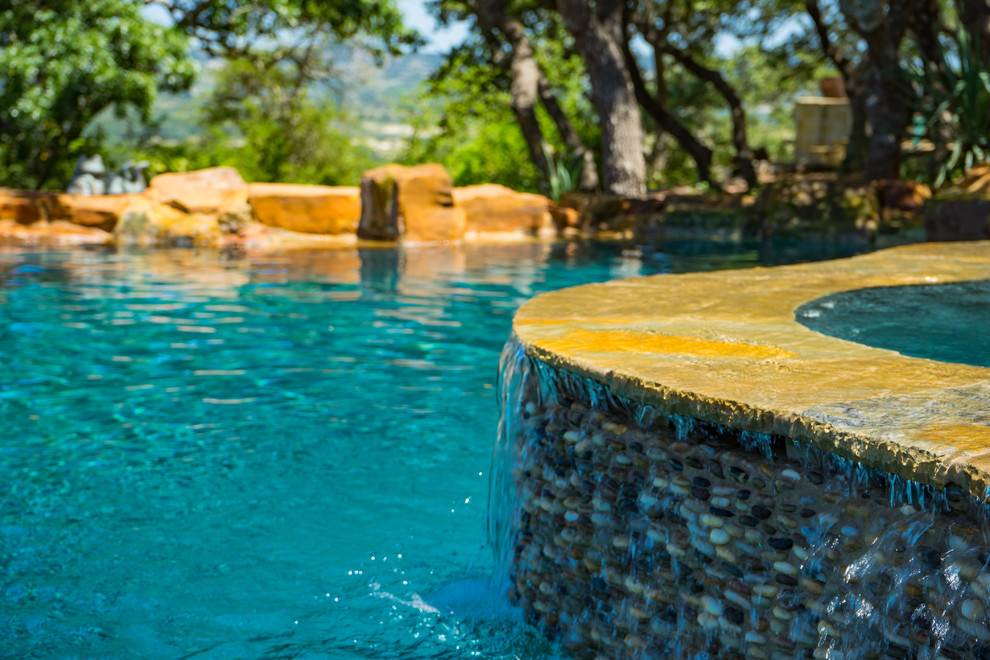 Cette image montre une piscine arrière chalet de taille moyenne et sur mesure avec un bain bouillonnant et des pavés en pierre naturelle.