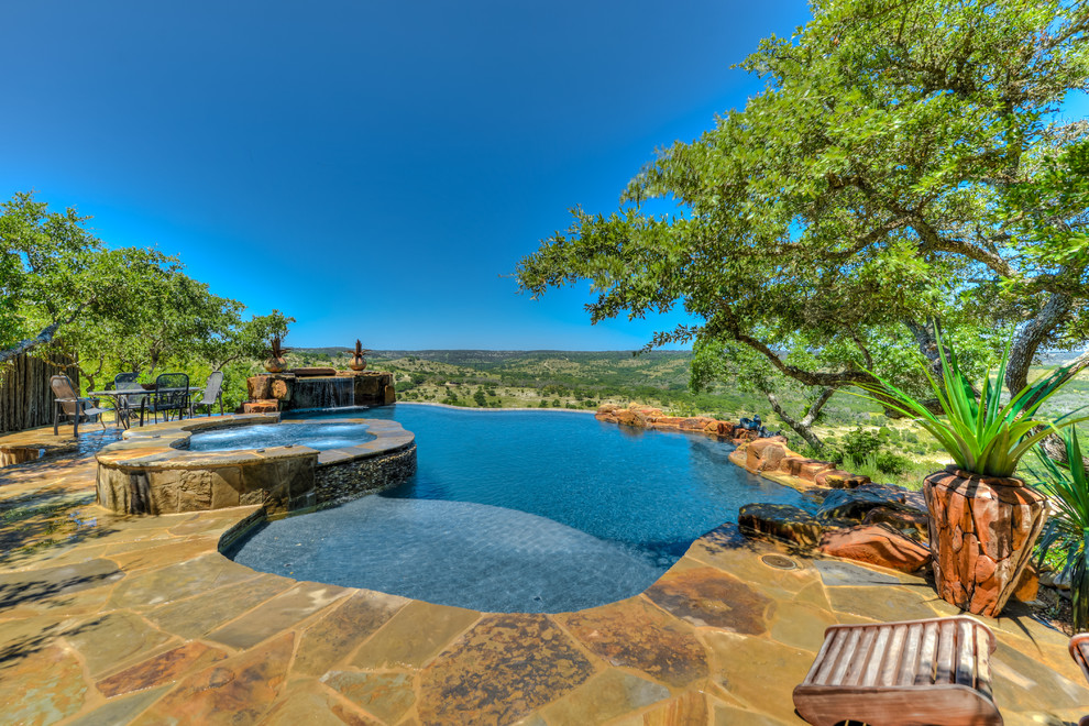 Cette photo montre une piscine arrière montagne de taille moyenne et sur mesure avec un bain bouillonnant et des pavés en pierre naturelle.