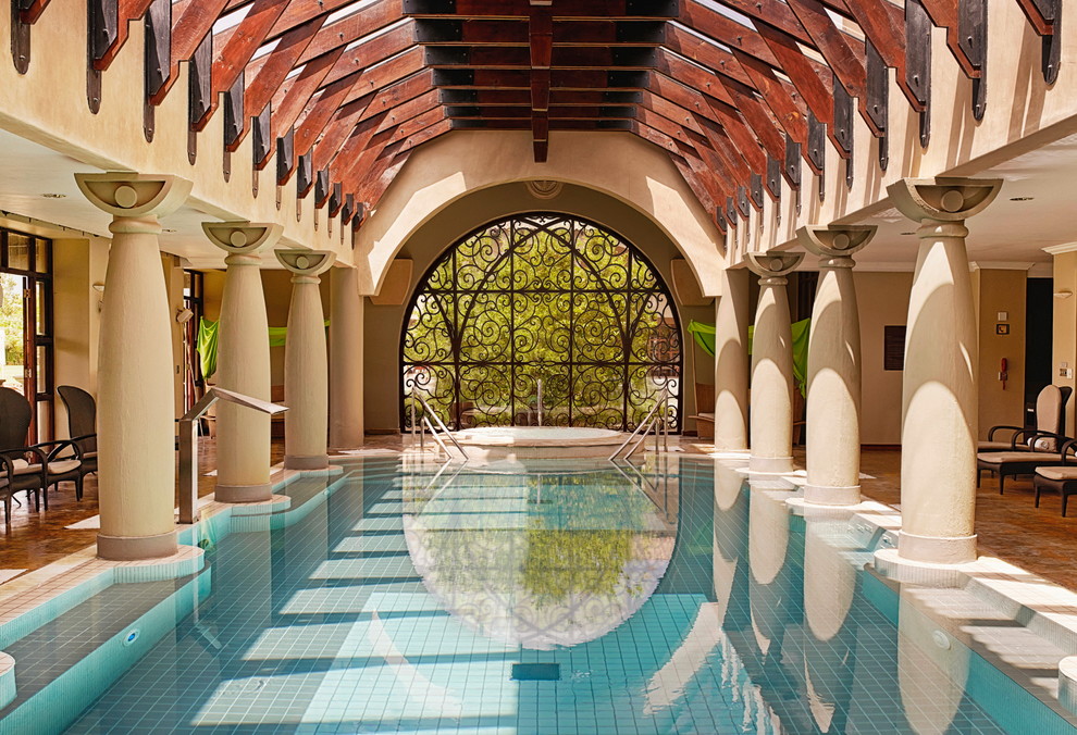 Esempio di una grande piscina coperta naturale mediterranea personalizzata con una vasca idromassaggio e piastrelle