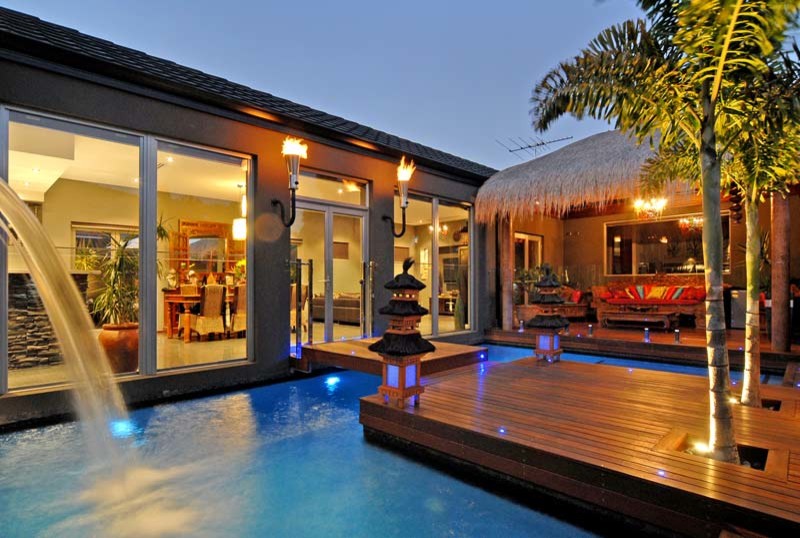 Idee per una grande piscina naturale tropicale personalizzata dietro casa con fontane e pedane
