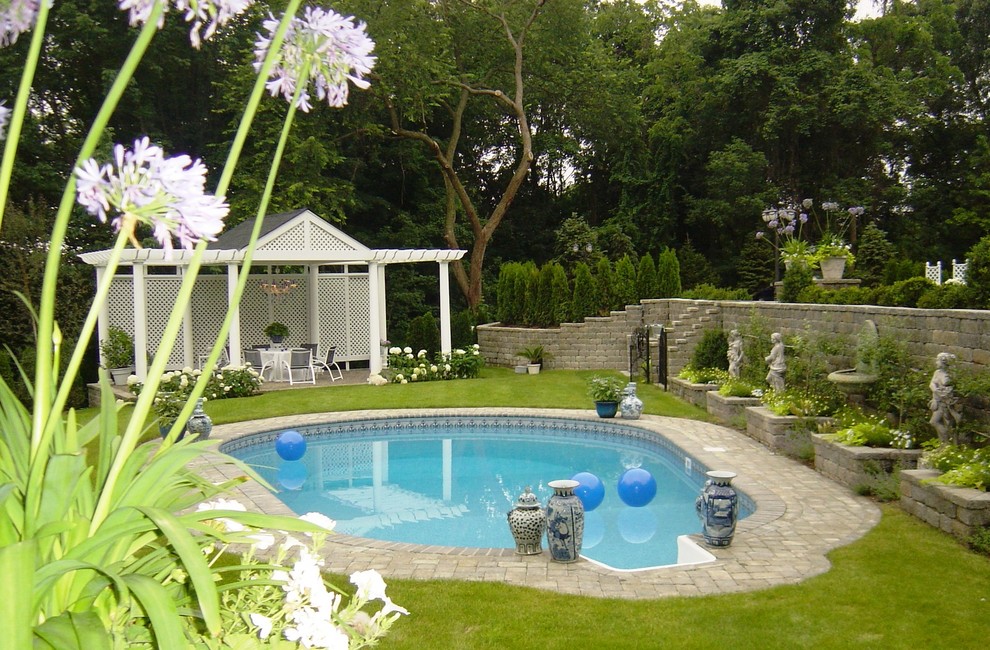 Idée de décoration pour un très grand Abris de piscine et pool houses arrière tradition sur mesure avec des pavés en pierre naturelle.