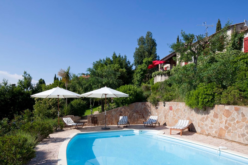 Foto de piscina mediterránea grande a medida en patio trasero con adoquines de piedra natural