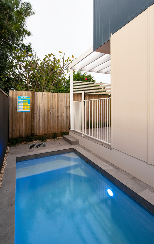Imagen de piscina alargada costera pequeña rectangular en patio con privacidad y suelo de baldosas