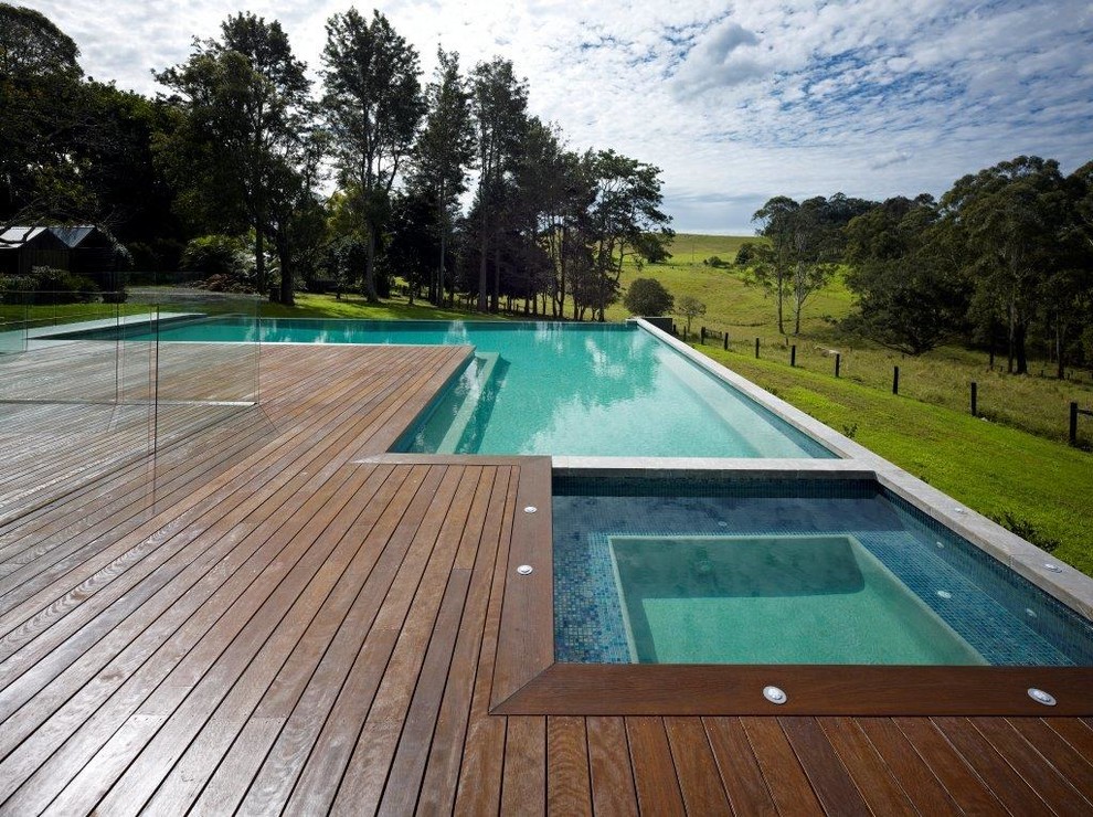Exempel på en modern l-formad pool på baksidan av huset, med trädäck