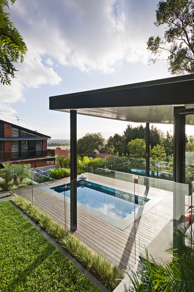 Exemple d'une grande piscine arrière tendance avec une terrasse en bois.