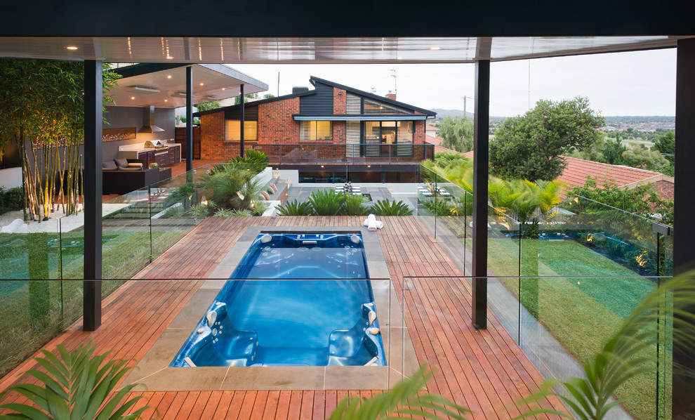 На фото: большой прямоугольный бассейн на заднем дворе в современном стиле с настилом