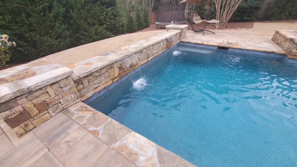 Foto de piscina con fuente natural rústica de tamaño medio rectangular en patio trasero con adoquines de hormigón